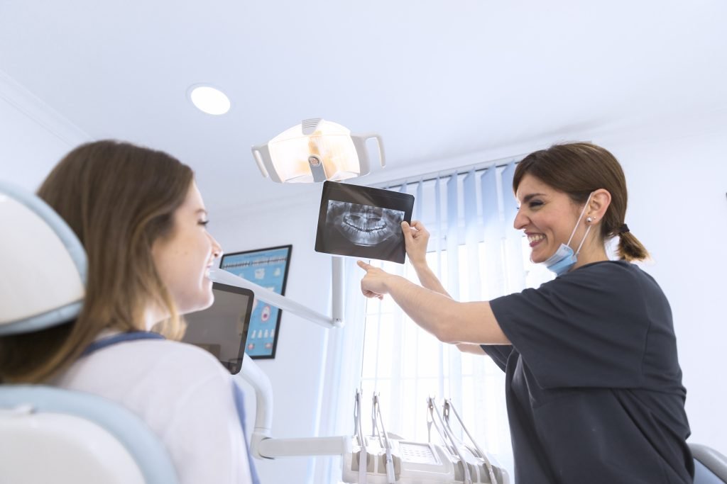 happy-smiling-female-dentist-showing-dental-x-ray-patient