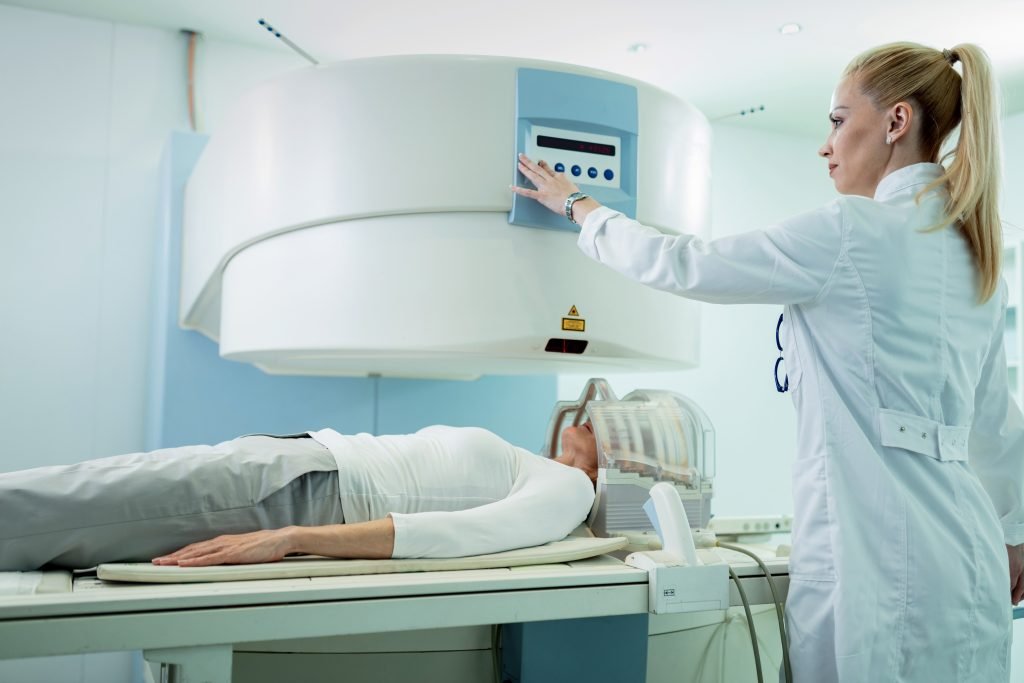 Female technician starting MRI scan of a patient at clinic.
